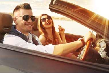 Güneşli bir günde üstü açık lüks bir arabada şık bir çift.