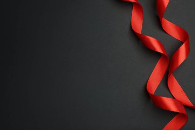 Koyu arkaplanda güzel kırmızı kurdeleler, düz yatış. Metin için boşluk