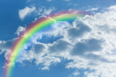 Parlak renkli gökkuşağı ve mavi gökyüzündeki bulutlar