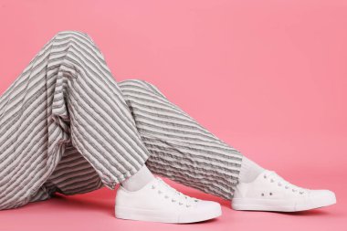 Pembe arka planda şık beyaz ayakkabılar giyen bir kadın, yakın plan. Metin için boşluk