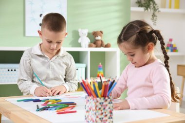 Çocuklar kalemle çizim yapıyorlar.