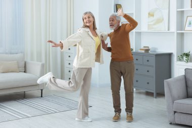 Mutlu yaşlı çift evde dans ediyor.