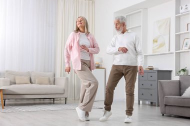 Mutlu yaşlı çift evde dans ediyor.