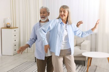 Mutlu yaşlı çift evde dans ediyor.