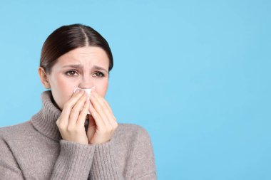 Açık mavi arka planda burnu akan bir kadın, mesaj için yer var. Soğuk Semptom