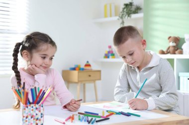 Çocuklar kalem ve pastel boyayla resim çiziyor.