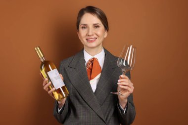 Kahverengi arka planda cam ve şarap şişesi olan profesyonel şarap garsonu.