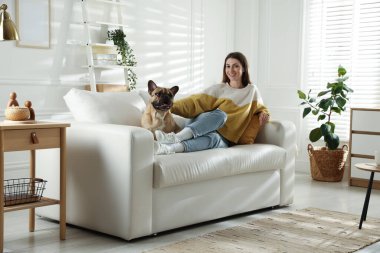 Evdeki kanepede tatlı köpeğiyle dinlenen bir kadın.