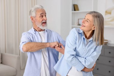 Mutlu yaşlı çift evde dans ediyor.