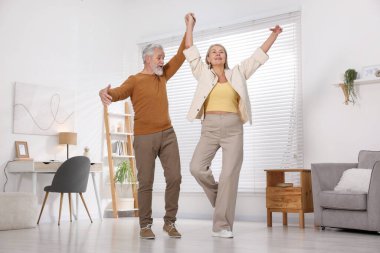 Mutlu yaşlı çift evde dans ediyor.