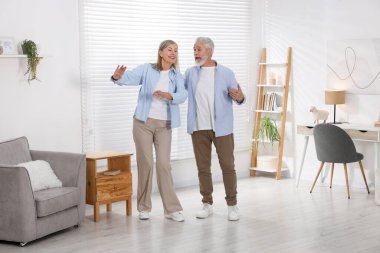 Mutlu yaşlı çift evde dans ediyor.