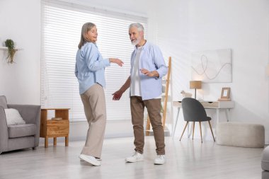 Mutlu yaşlı çift evde dans ediyor.