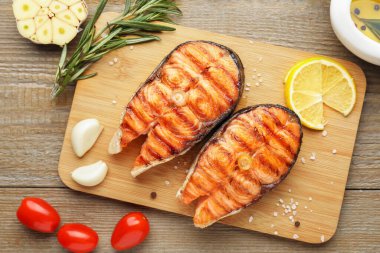 Ahşap masada servis edilen leziz ızgara somon biftekleri.