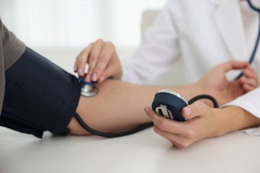 Doktor kan basıncını hastanedeki masada sphygmomanometre ile ölçüyor.