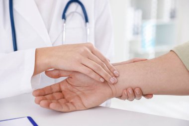 Doktor masadaki parmaklarıyla adamın nabzını kontrol ediyor.