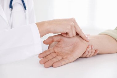 Doktor masadaki parmaklarıyla adamın nabzını kontrol ediyor.