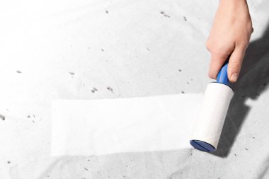 Beyaz kumaş üzerinde pamuk rulo kullanan kadın, yakın plan.