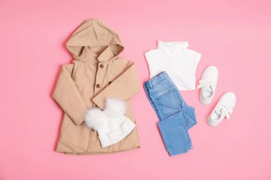 Pembe arka planda şık çocuk kıyafetleri ve ayakkabıları var.
