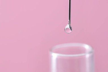Tüp bebek tedavisinde. Sıvı numuneli iğne ve pembe arka planda test tüpü, yakın plan. Metin için boşluk