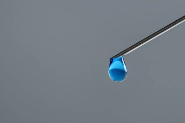 Tüp bebek tedavisinde. Gri arka planda sıvı numunesi olan iğne, yakın plan. Metin için boşluk