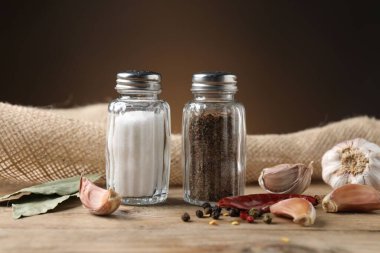 Ahşap masa üzerinde baharatlı tuzluk ve biber karıştırıcılar kahverengi eğimli arka plan, yakın çekim