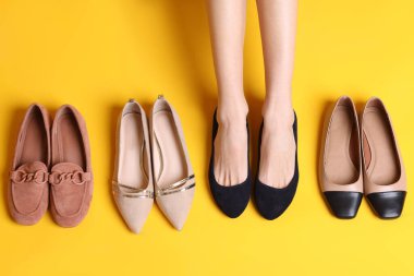 Sarı arka planda farklı ayakkabıları olan bir kadın.