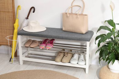 Farklı ayakkabılar, aksesuarlar ve beyaz duvarın yanındaki ev bitkilerinden oluşan ayakkabı deposu.