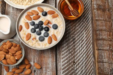 Badem sütlü yulaf ezmesi, fındık, bal ve yaban mersinli ahşap masa, düz yatak. Metin için boşluk