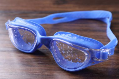 Su damlaları ile yüzme gözlükleri ahşap masaya, yakın plan