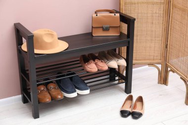 Evin içinde tozlu pembe duvarın yanında farklı ayakkabı ve aksesuarlarla dolu ayakkabı deposu.