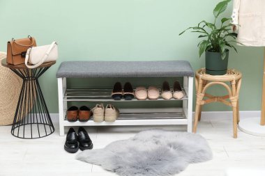 Farklı ayakkabı, aksesuar ve yeşil duvarın yanındaki ev bitkilerinden oluşan ayakkabı deposu.