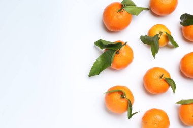 Beyaz arka planda olgun mandalinalar ve yeşil yapraklar. Metin için boşluk