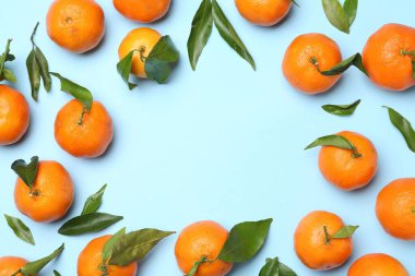 Taze mandalina ve açık mavi arka planda yeşil yapraklar, düz. Metin için boşluk