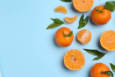 Taze mandalina ve açık mavi arka planda yeşil yapraklar, düz. Metin için boşluk