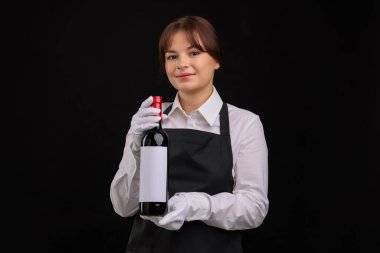 Siyah arka planda kırmızı şarap şişesi olan profesyonel şarap garsonu.