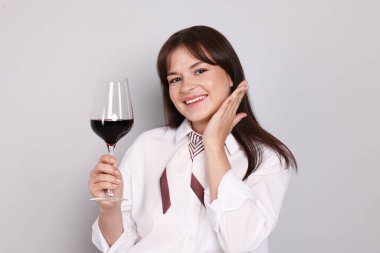 Açık gri arka planda kırmızı şarap kadehi olan profesyonel şarap garsonu.