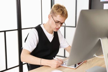 Ofisteki ahşap masada tablet üzerinde çalışan tasarımcı