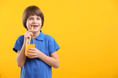 Sarı arka planda bir bardak taze portakal suyu olan çocuk. Metin için boşluk