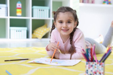 Evde yerde kalemle resim yapan şirin küçük bir kız. Metin için boşluk