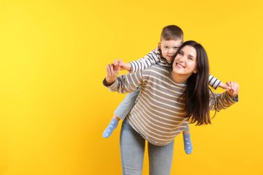 Sarı arka planda oğluyla mutlu anne, mesaj için yer var.