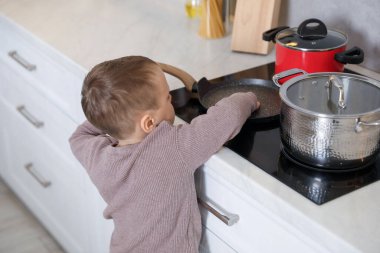 Evde çocuk güvenliği. Küçük çocuk mutfakta ocakla oynuyor.