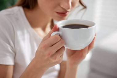 Evde bir fincan aromalı kahveli kadın, yakın plan.