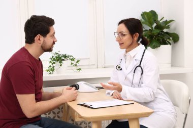 Klinikteki ahşap masada pano danışmanı olan bir doktor.