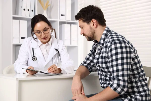 Klinikteki beyaz masada pano danışmanı olan bir doktor.