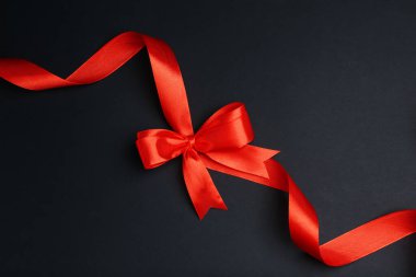 Koyu arka planda fiyonklu güzel kırmızı kurdele, üst manzara