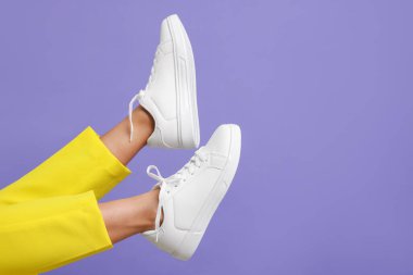 Violet 'in arka planında şık beyaz ayakkabılar giyen bir kadın, yakın plan. Metin için boşluk