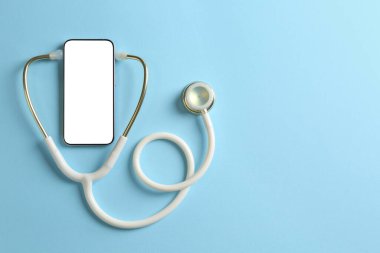 Sağlığınıza. Açık mavi arka planda steteskoplu akıllı telefon, üst manzara. Metin için boşluk