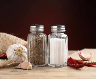 Ahşap masada baharatlı tuzluk ve biberlikler koyu arka planda, yakın planda.