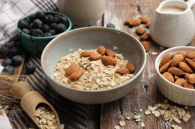 Yulaf gevreği, fındık, badem sütü ve yaban mersini ahşap masada, yakın plan.