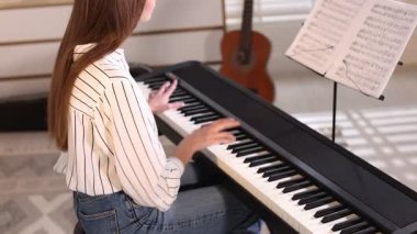 Evde sentezleyici oynayan bir kadın, yakın plan. Müzik aleti